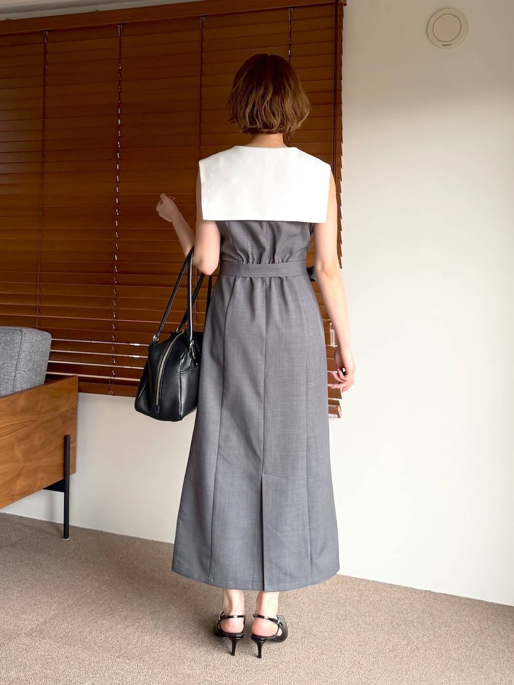 ブラック系のハンドバッグ、ブラック系のサンダル、グレー系のワンピースを着用したレディースの春コーディネートの3枚目の写真