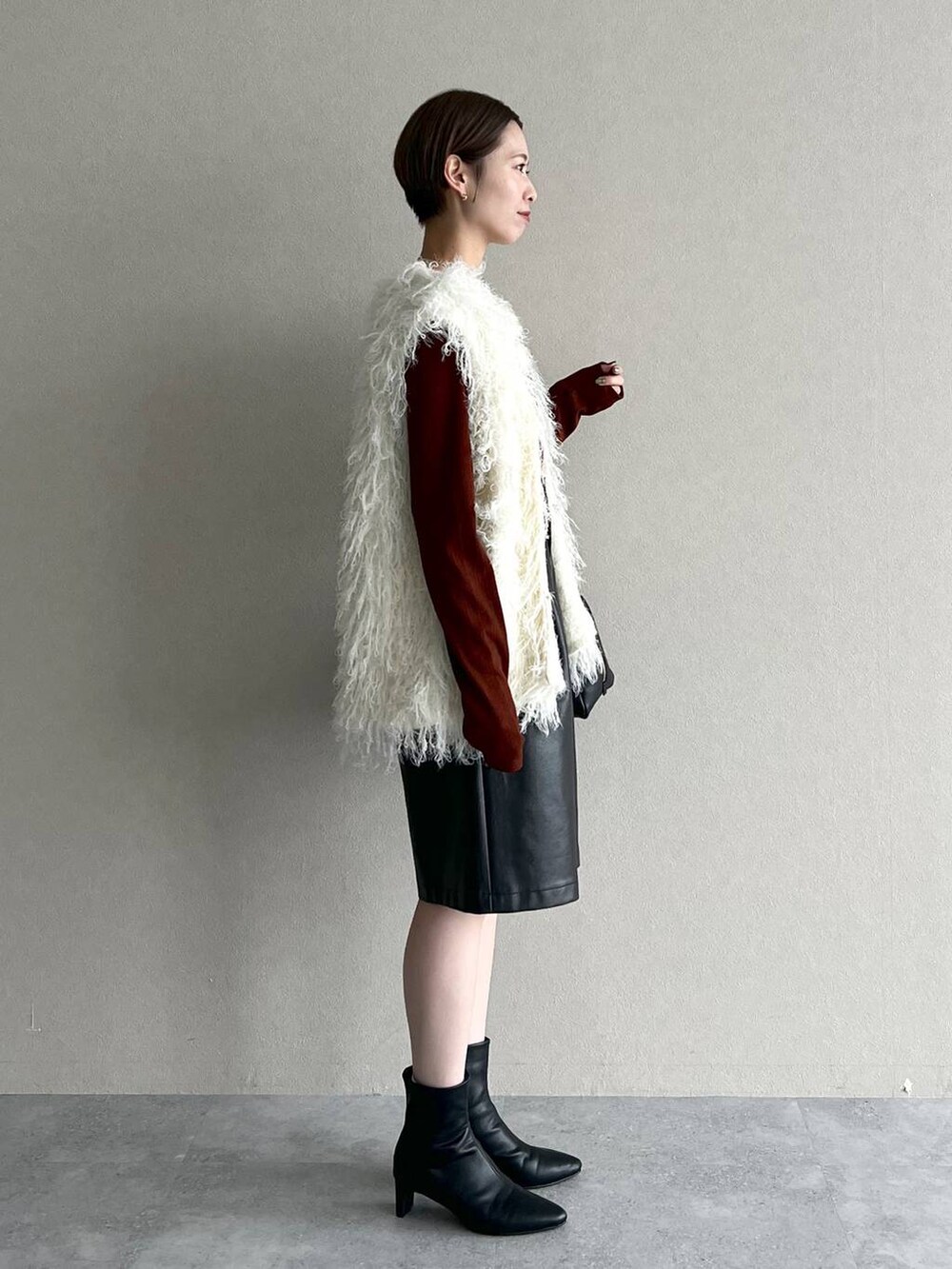 ブラック系のハンドバッグ、ホワイト系のベスト、ブラウン系のTシャツ/カットソーを着用したレディースの秋コーディネートの2枚目の写真