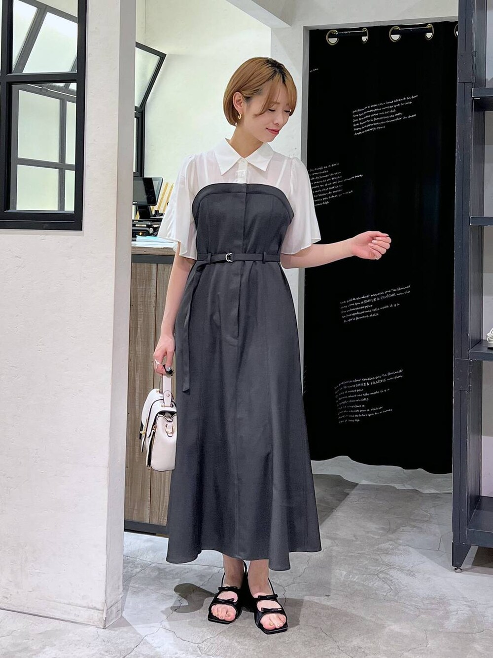 ブラック系のサンダル、グレー系のワンピース、ホワイト系のショルダーバッグを着用したレディースの春コーディネートの2枚目の写真