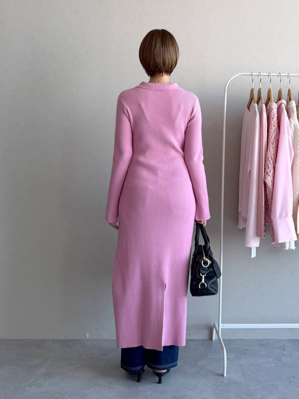 ブラック系のボストンバッグ、ピンク系のワンピース、ブルー系のデニムパンツを着用したレディースの冬コーディネートの3枚目の写真