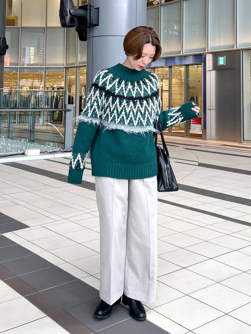 ブラック系のトートバッグ、ブラック系のブーツ、グリーン系のニット/セーターを着用したレディースの秋コーディネートの5枚目の写真