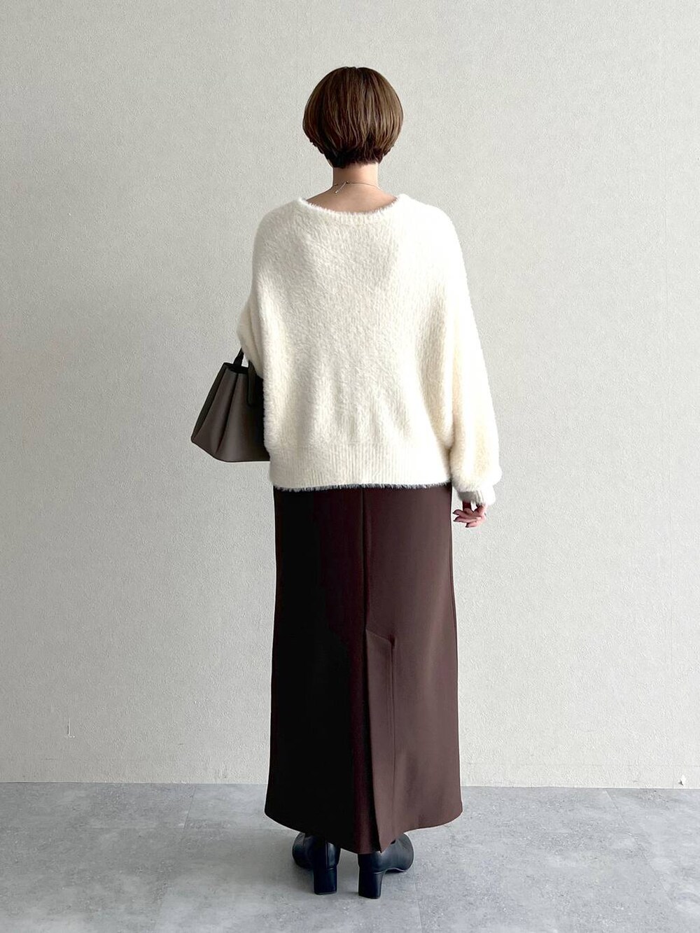 ベージュ系のショルダーバッグ、ブラウン系のスカート、ブラック系のブーツを着用したレディースの秋コーディネートの3枚目の写真