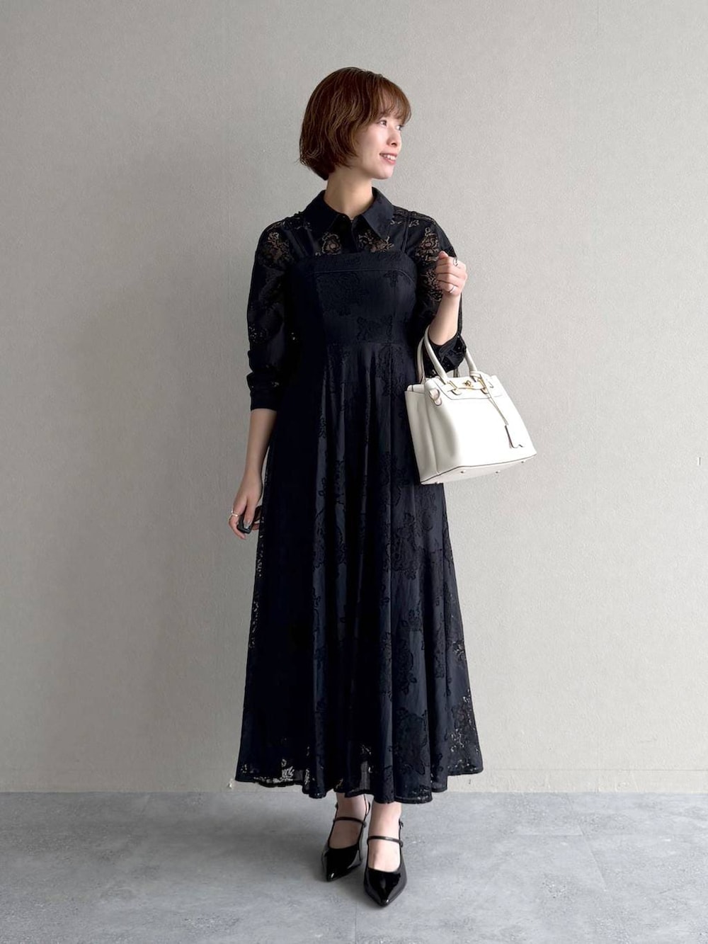 ブラック系のサンダル、ブラック系のワンピース、ホワイト系のショルダーバッグを着用したレディースの春コーディネートの5枚目の写真