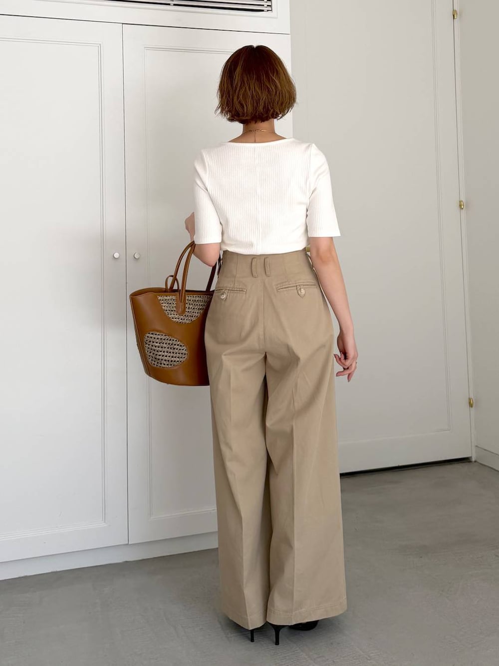 ブラウン系のトートバッグ、ブラック系のサンダル、ホワイト系のTシャツ/カットソーを着用したレディースの春コーディネートの3枚目の写真