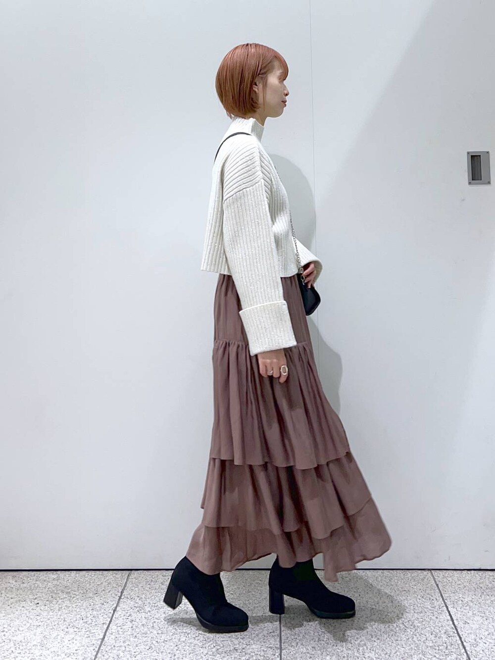 ブラック系のボストンバッグ、ブラック系のブーツ、ブラウン系のスカートを着用したレディースの冬コーディネートの2枚目の写真