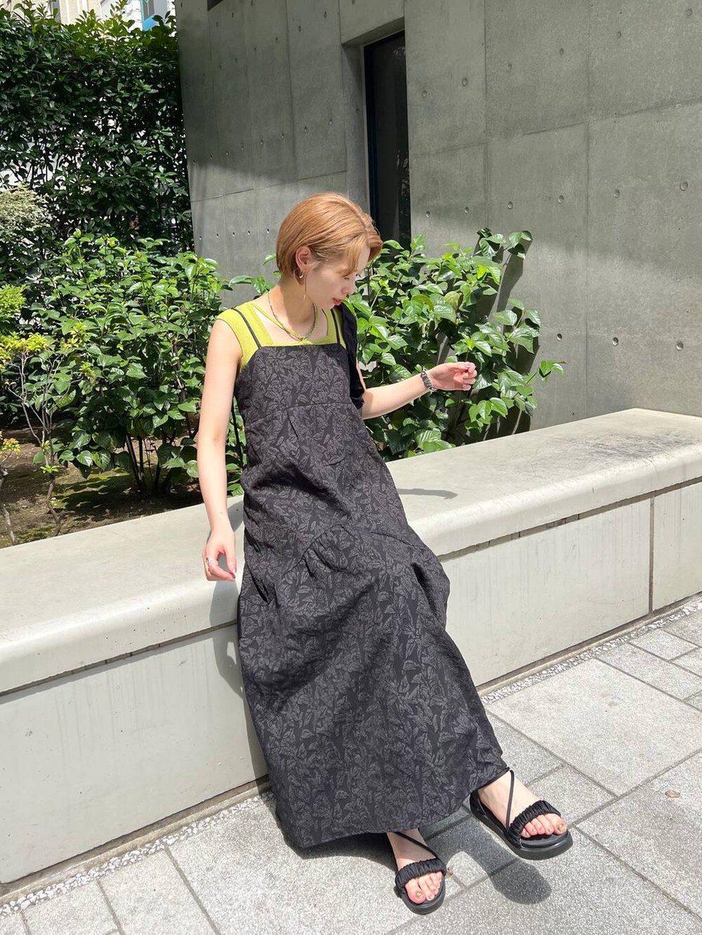 ブラック系のサンダル、グリーン系のニット/セーター、ブラック系のワンピースを着用したレディースの夏コーディネートの2枚目の写真