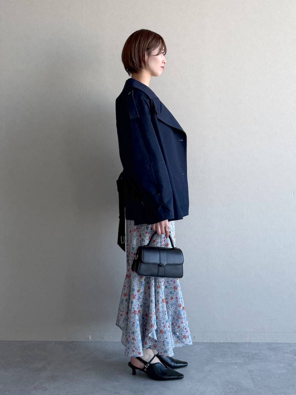 ブラック系のショルダーバッグ、ブラック系のサンダル、ブルー系のトレンチコートを着用したレディースの冬コーディネートの2枚目の写真