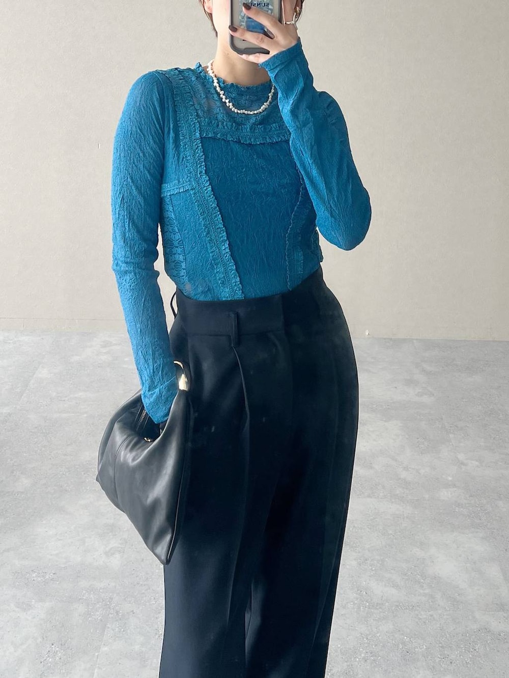 ブラック系のハンドバッグ、ブルー系のTシャツ/カットソー、ブルー系のスラックスを着用したレディースの秋コーディネートの6枚目の写真