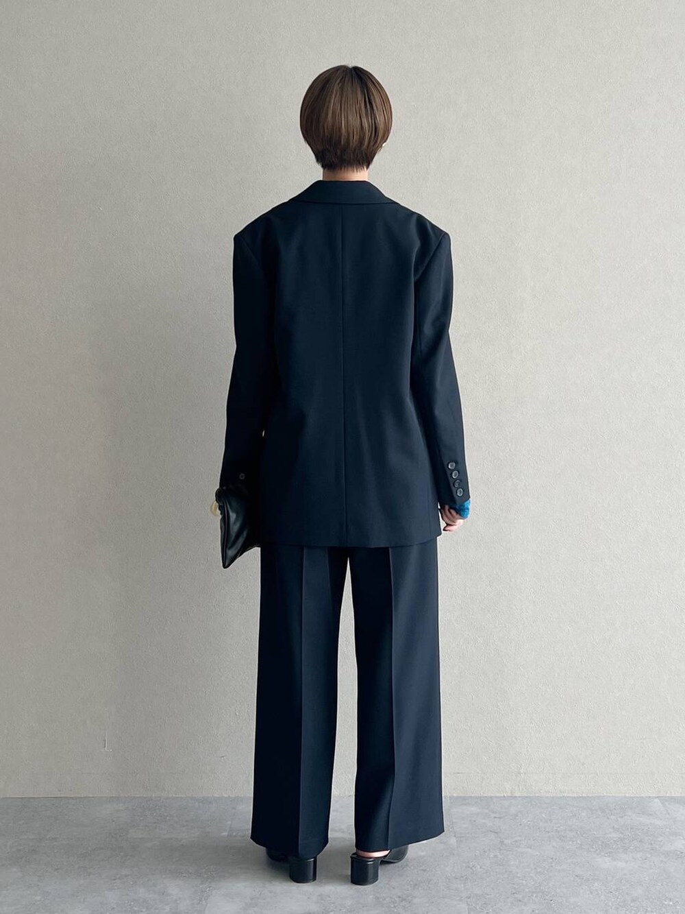 ブラック系のハンドバッグ、ブルー系のTシャツ/カットソー、ブルー系のスラックスを着用したレディースの秋コーディネートの3枚目の写真