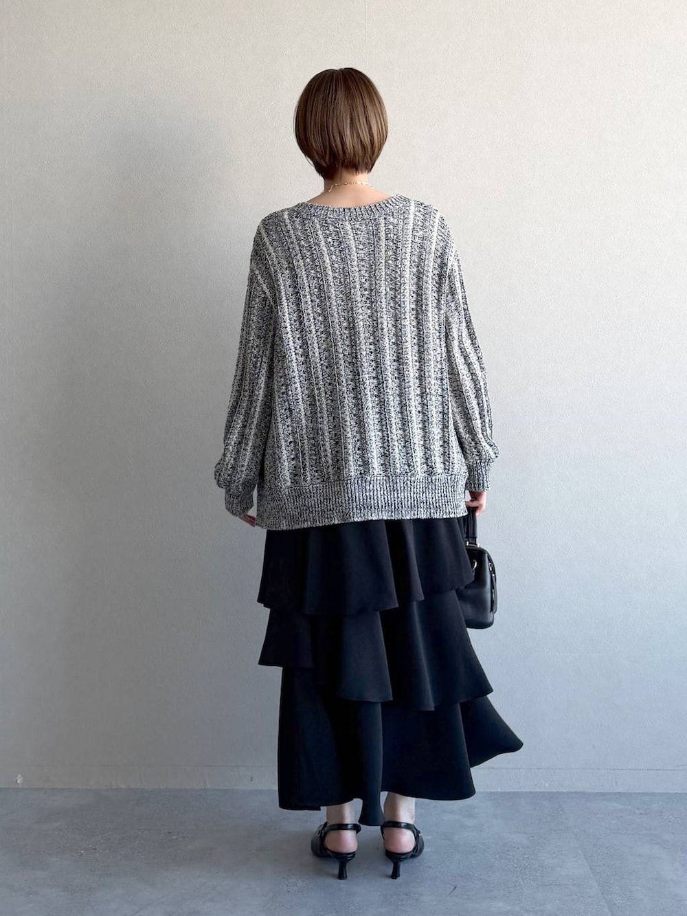 ブラック系のショルダーバッグ、ブラック系のサンダル、ホワイト系のニット/セーターを着用したレディースの冬コーディネートの3枚目の写真