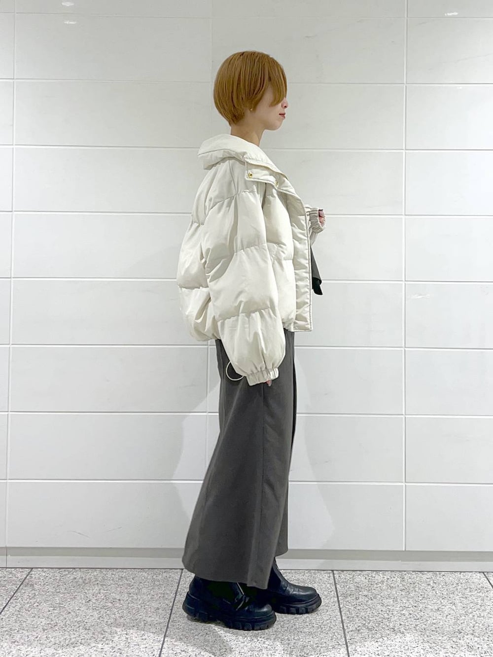 ブラック系のブーツ、ブラック系のニット/セーター、ホワイト系のブルゾンを着用したレディースの冬コーディネートの2枚目の写真