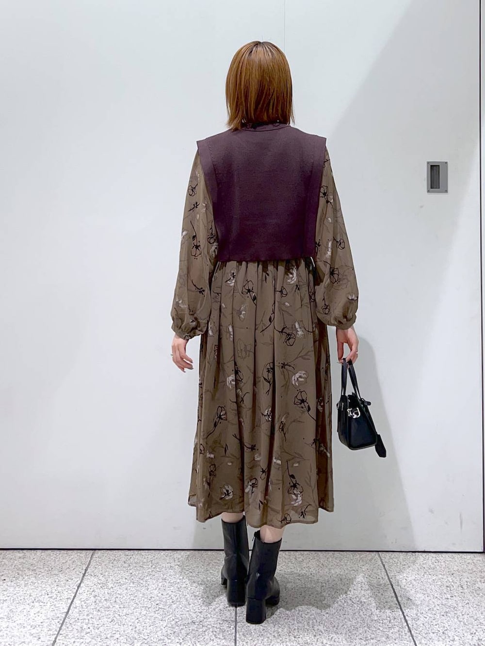 ホワイト系のチェスターコート、ブラック系のボストンバッグ、ブラック系のブーツを着用したレディースの秋コーディネートの6枚目の写真