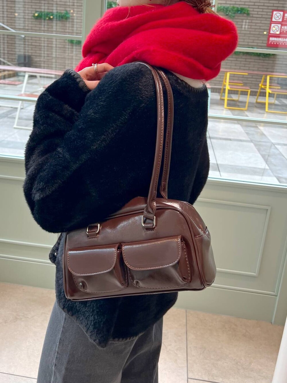 ブラック系のデニムパンツ、ブラック系のブーツ、ブラウン系のハンドバッグを着用したレディースの秋コーディネートの5枚目の写真