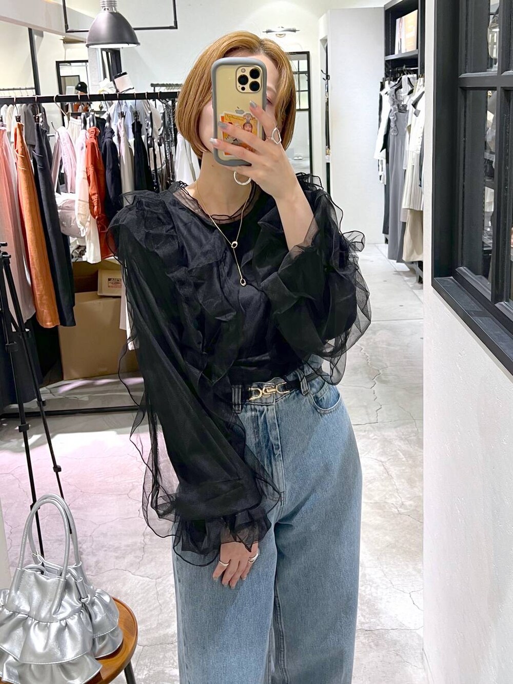 ブルー系のデニムパンツ、シルバー系のショルダーバッグ、ブラック系のシャツ/ブラウスを着用したレディースの秋コーディネートの5枚目の写真