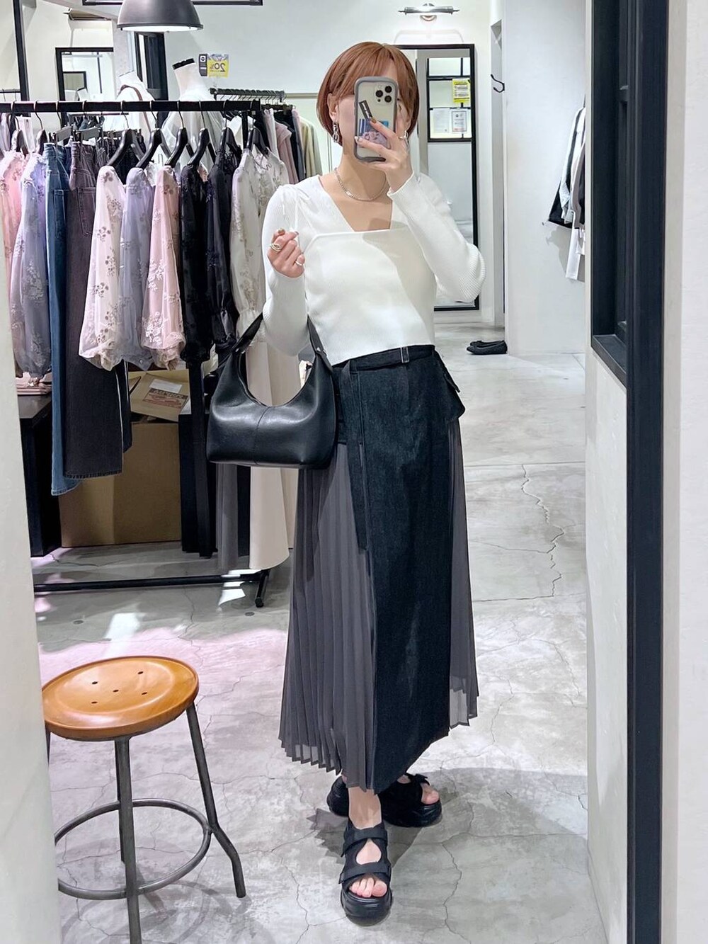 ブラック系のスカート、ホワイト系のカーディガン/ボレロ、ブラック系のサンダルを着用したレディースの春コーディネートの5枚目の写真