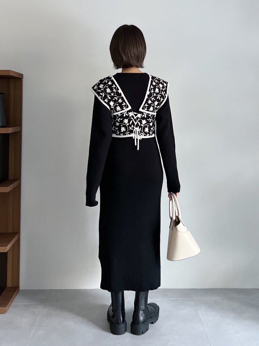 ブラック系のワンピース、ホワイト系のバッグ、ブラック系のブーツを着用したレディースの秋コーディネートの3枚目の写真