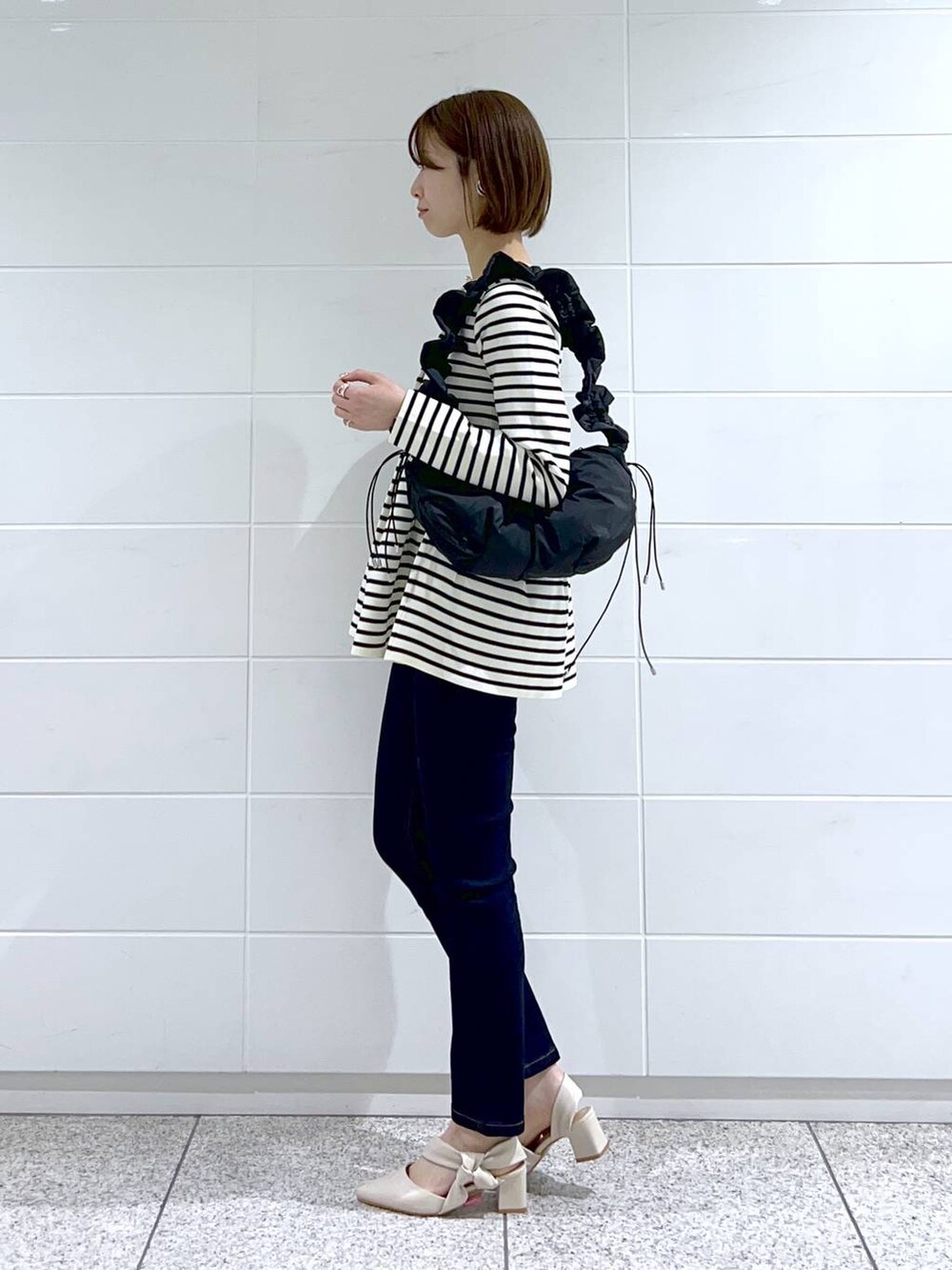 ホワイト系のカーディガン/ボレロ、ブルー系のデニムパンツ、ブラック系のハンドバッグを着用したレディースの春コーディネートの2枚目の写真