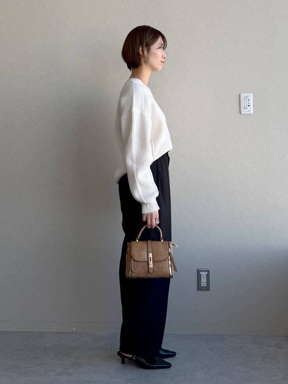 ブラック系のローファー、ブラウン系のショルダーバッグ、ホワイト系のニット/セーターを着用したレディースの冬コーディネートの2枚目の写真