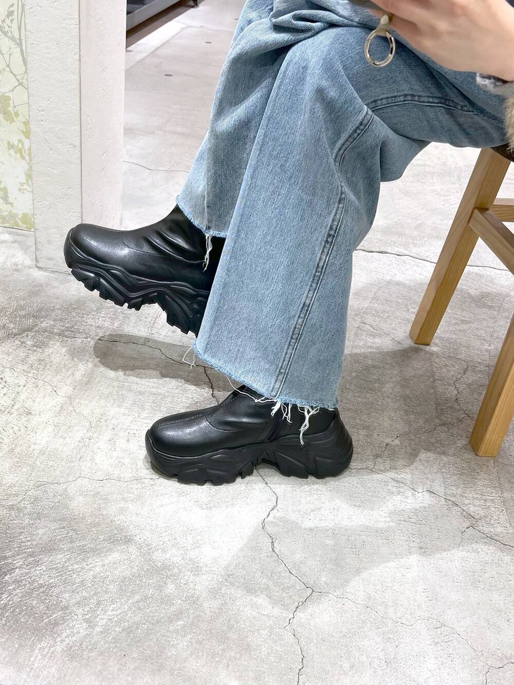 ブルー系のデニムパンツ、ブラック系のブーツ、ブラック系のショルダーバッグを着用したレディースの秋コーディネートの5枚目の写真