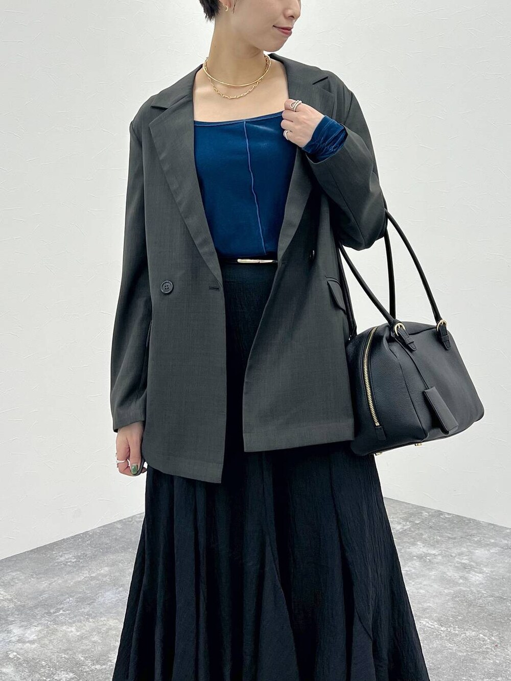 グレー系のテーラードジャケット、ブラック系のハンドバッグ、ブラック系のスカートを着用したレディースの秋コーディネートの8枚目の写真