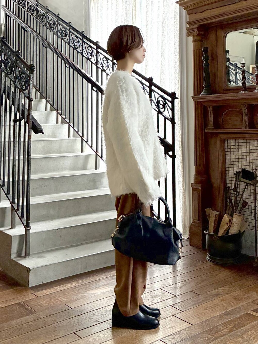 ブラック系のボストンバッグ、ブラウン系のスラックス、ホワイト系のニット/セーターを着用したレディースの秋コーディネートの2枚目の写真