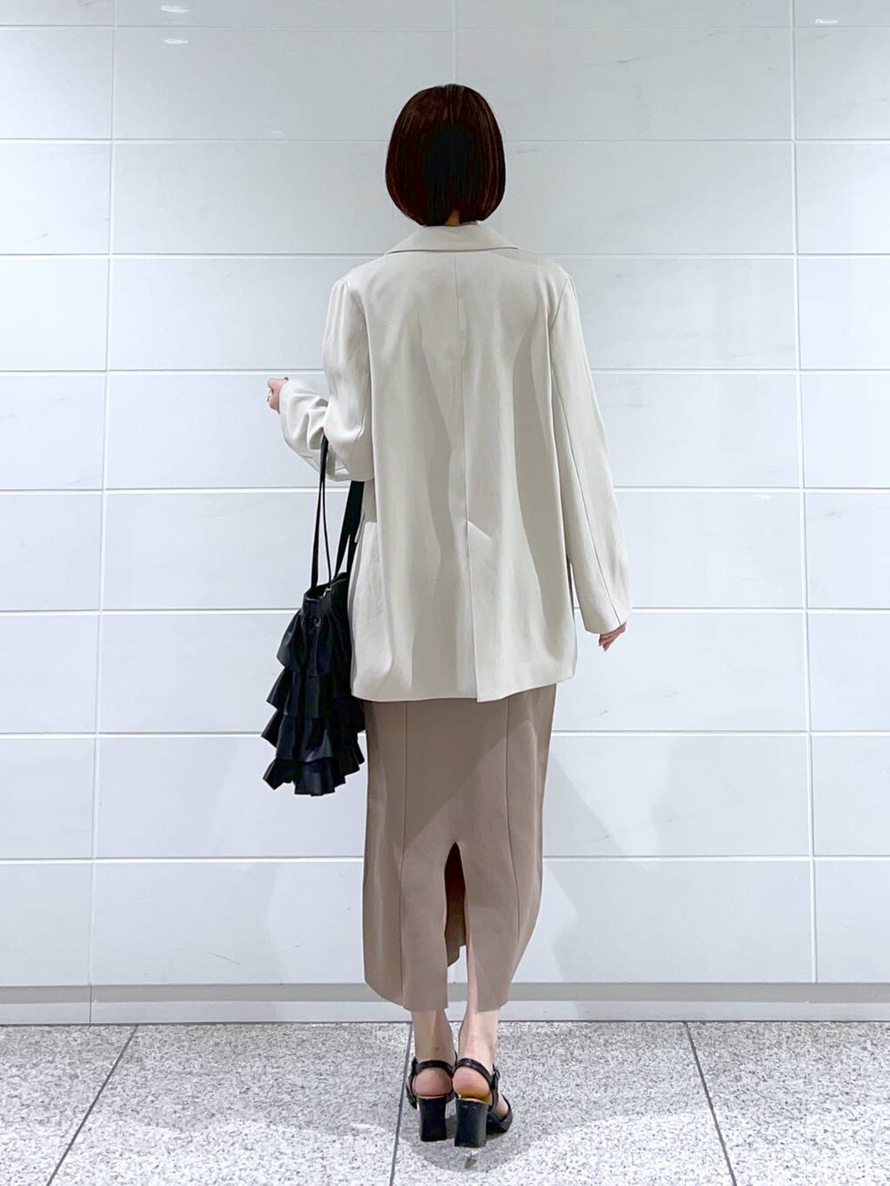 ホワイト系のテーラードジャケット、ブラック系のパンプス、ブラック系のトートバッグを着用したレディースの冬コーディネートの3枚目の写真