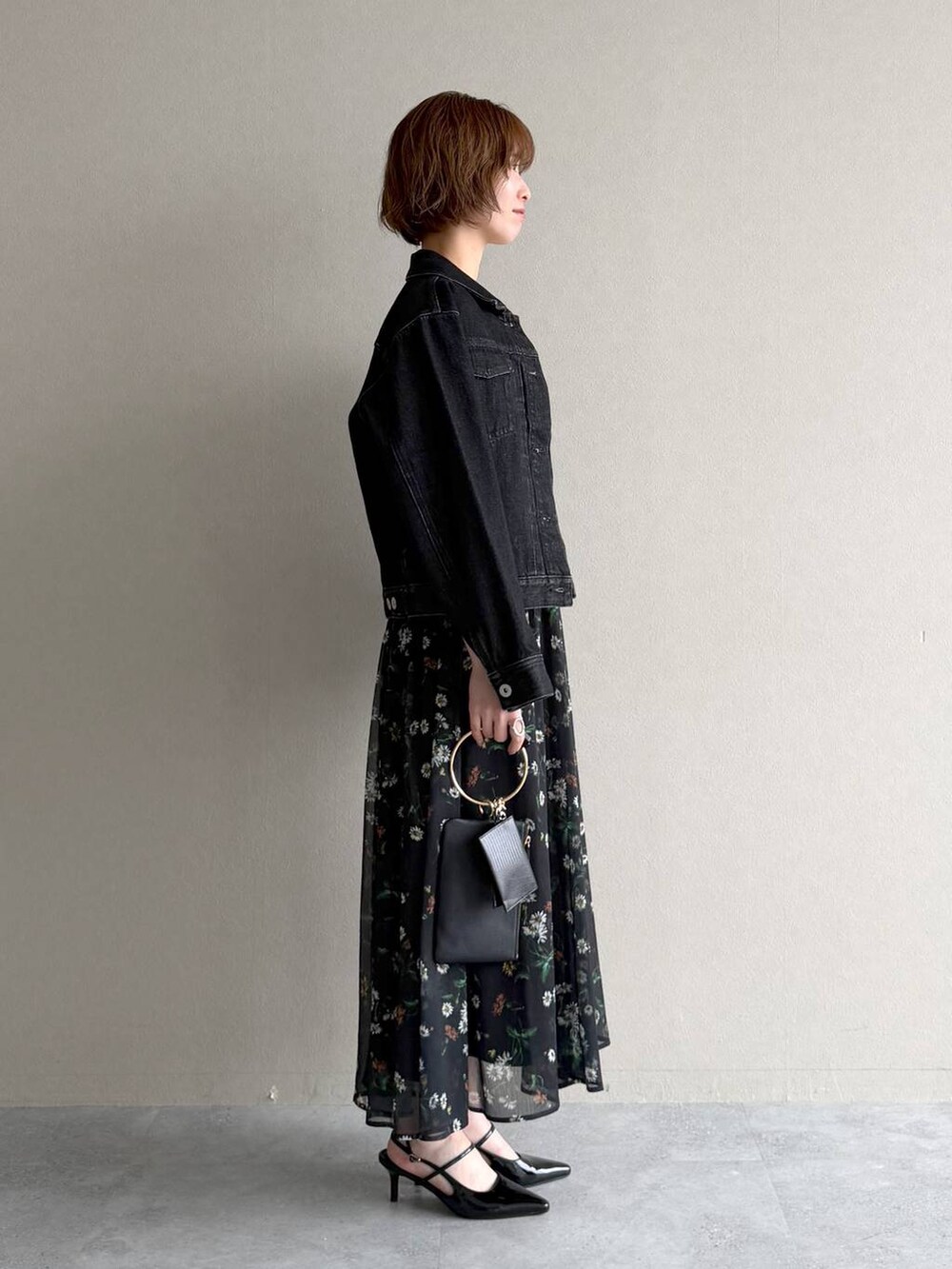 ブラック系のデニムジャケット、ブラック系のサンダル、ブラック系のショルダーバッグを着用したレディースの春コーディネートの2枚目の写真