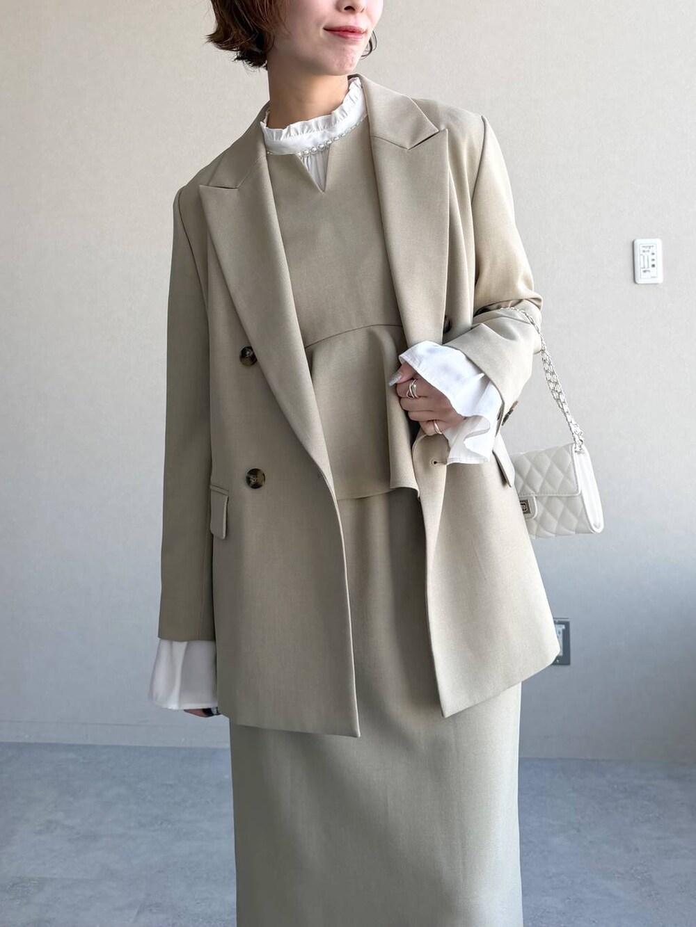 ベージュ系のテーラードジャケット、ベージュ系のワンピース、ホワイト系のシャツ/ブラウスを着用したレディースの冬コーディネートの7枚目の写真