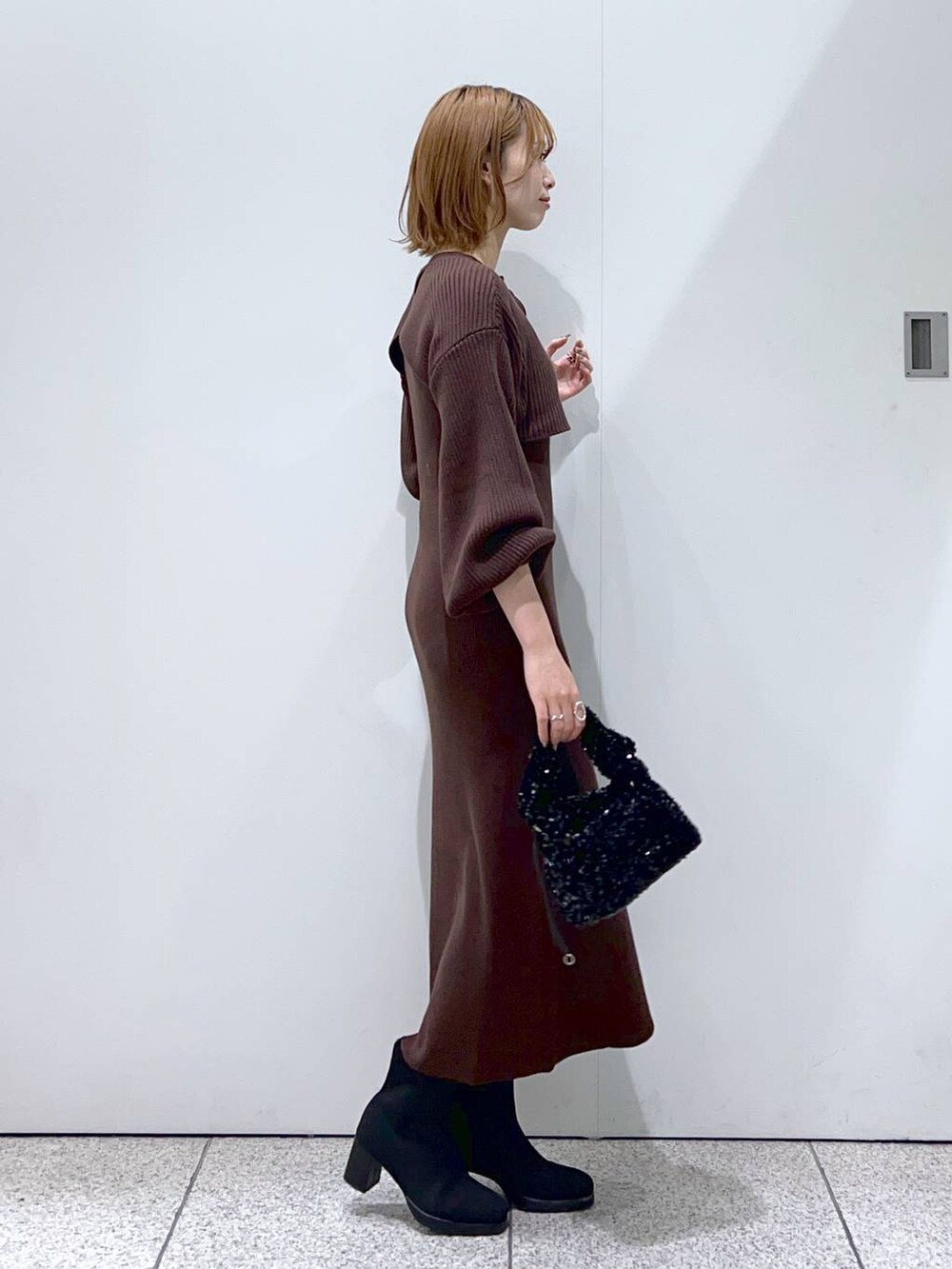 ブラック系のブーツ、ブラック系のハンドバッグ、ブラウン系のワンピースを着用したレディースの秋コーディネートの2枚目の写真