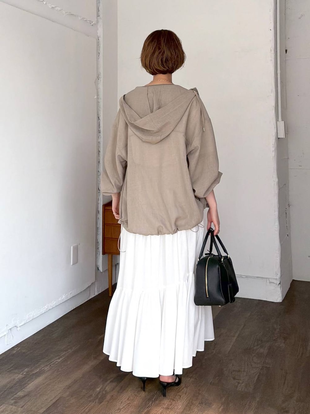 ブラック系のハンドバッグ、ブラック系のサンダル、ホワイト系のスカートを着用したレディースの春コーディネートの3枚目の写真