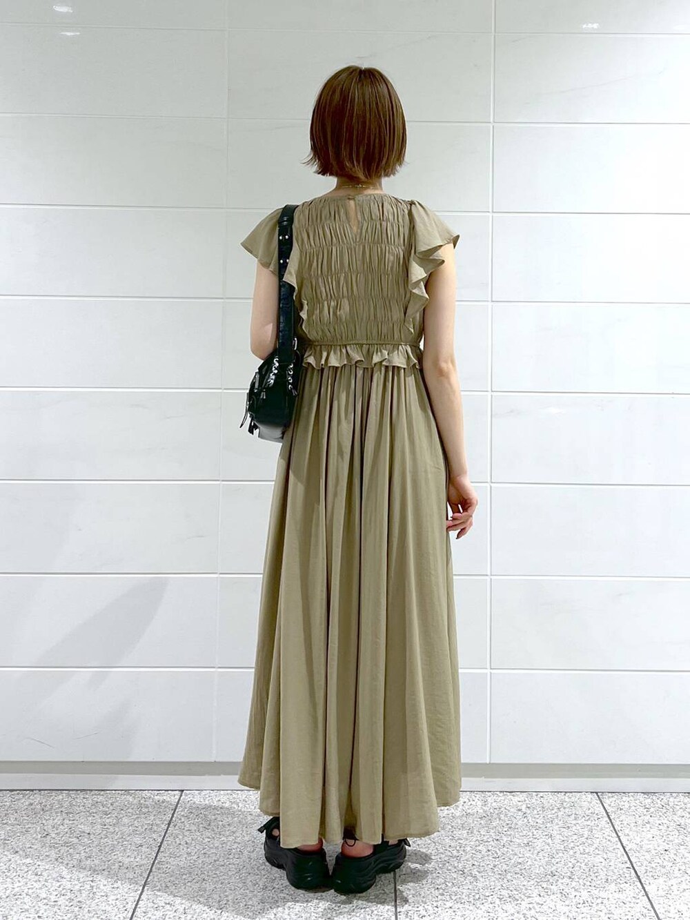 ブラック系のサンダル、ブラック系のショルダーバッグ、ベージュ系のワンピースを着用したレディースの春コーディネートの3枚目の写真