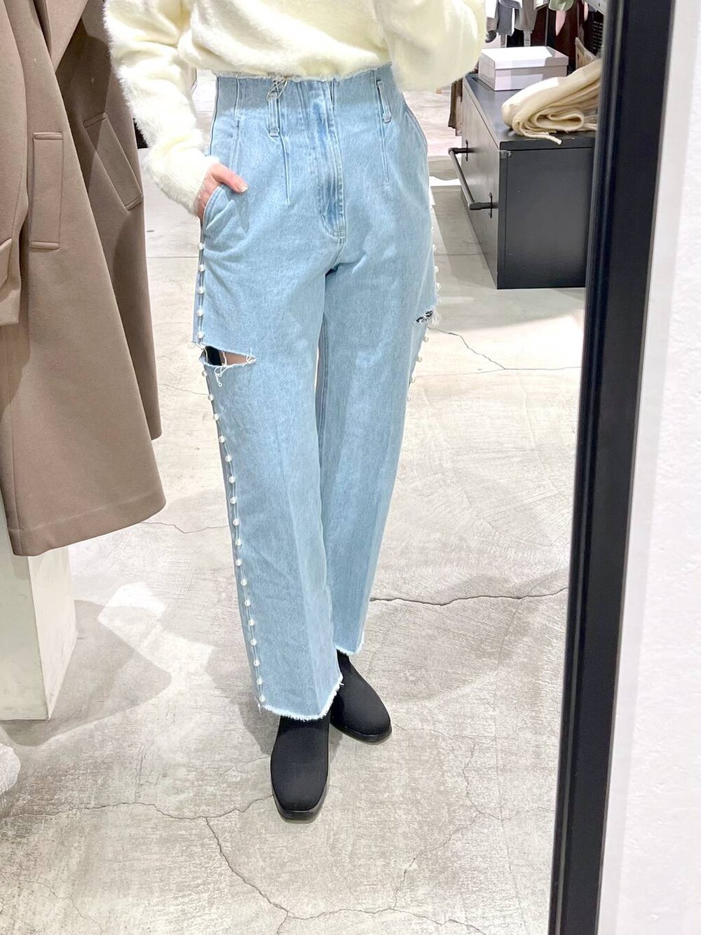 ホワイト系のニット/セーター、ブラウン系のチェスターコート、ブラック系のブーツを着用したレディースの冬コーディネートの7枚目の写真