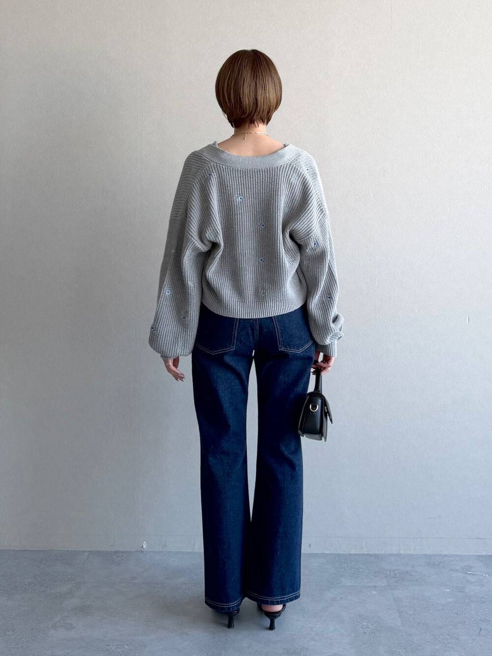 ブラック系のショルダーバッグ、ブルー系のデニムパンツ、ブラック系のサンダルを着用したレディースの冬コーディネートの3枚目の写真