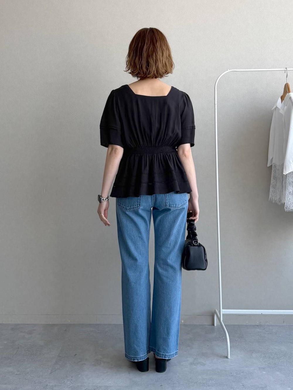 ブルー系のデニムパンツ、ブラック系のキャミソール、ブラック系のショルダーバッグを着用したレディースの春コーディネートの3枚目の写真