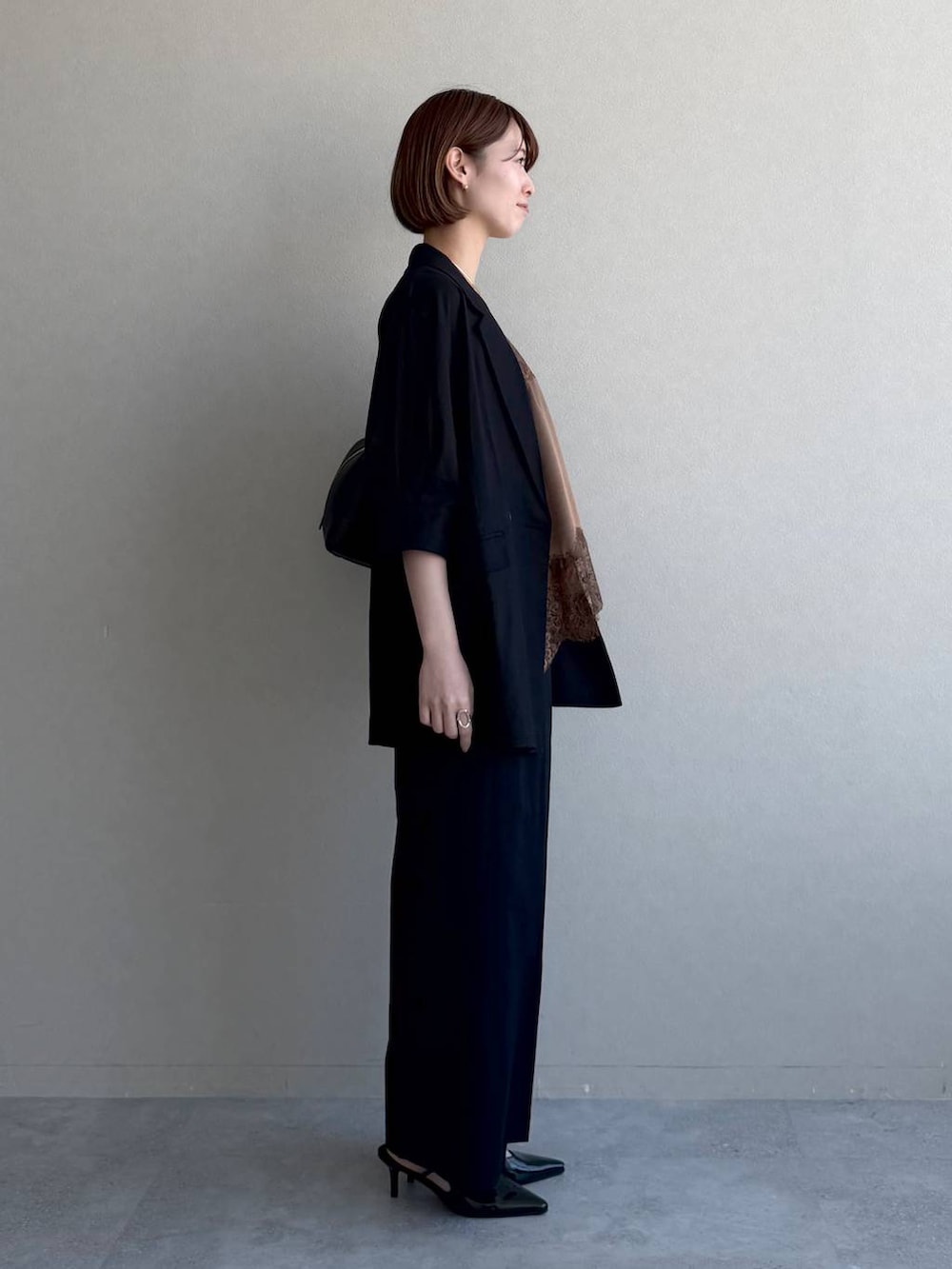 ブラック系のハンドバッグ、ブラック系のサンダル、ブラウン系のキャミソールを着用したレディースの春コーディネートの2枚目の写真