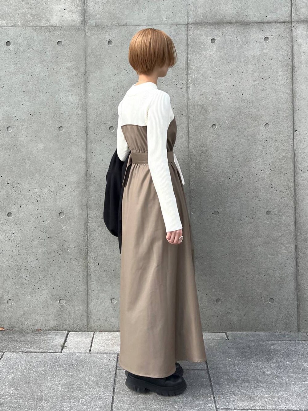 ブラック系のノーカラーコート、ブラック系のブーツ、ホワイト系のショルダーバッグを着用したレディースの冬コーディネートの5枚目の写真