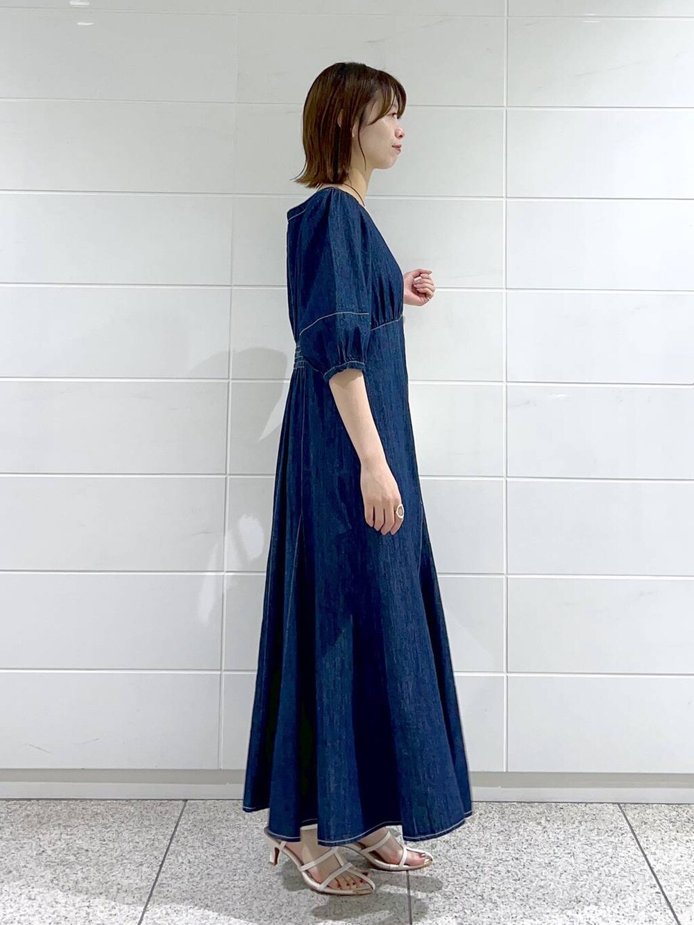 ブルー系のワンピース、ホワイト系のサンダル、ホワイト系のハンドバッグを着用したレディースの春コーディネートの3枚目の写真