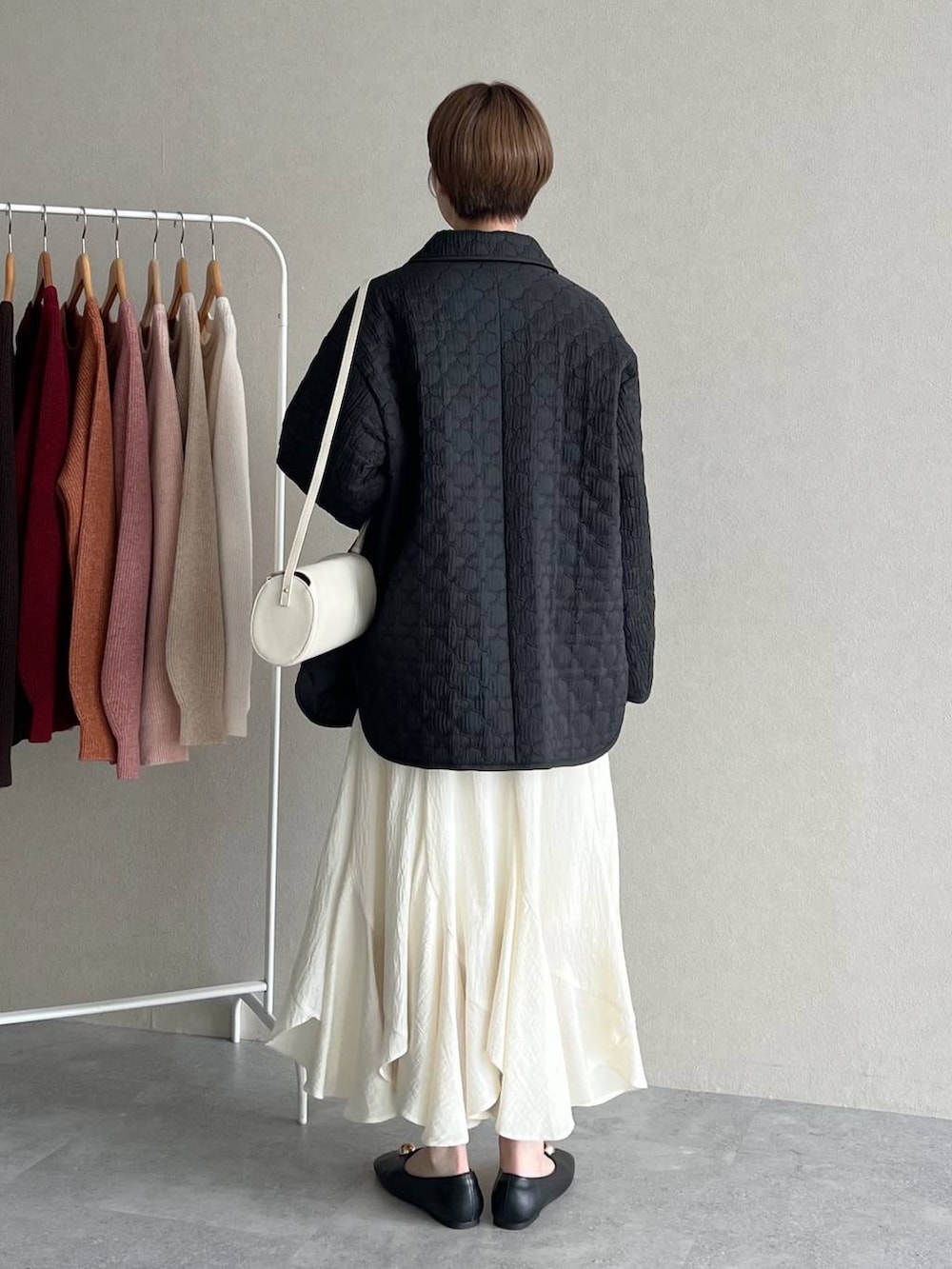 ホワイト系のスカート、ブラック系のブルゾン、ホワイト系のショルダーバッグを着用したレディースの秋コーディネートの3枚目の写真