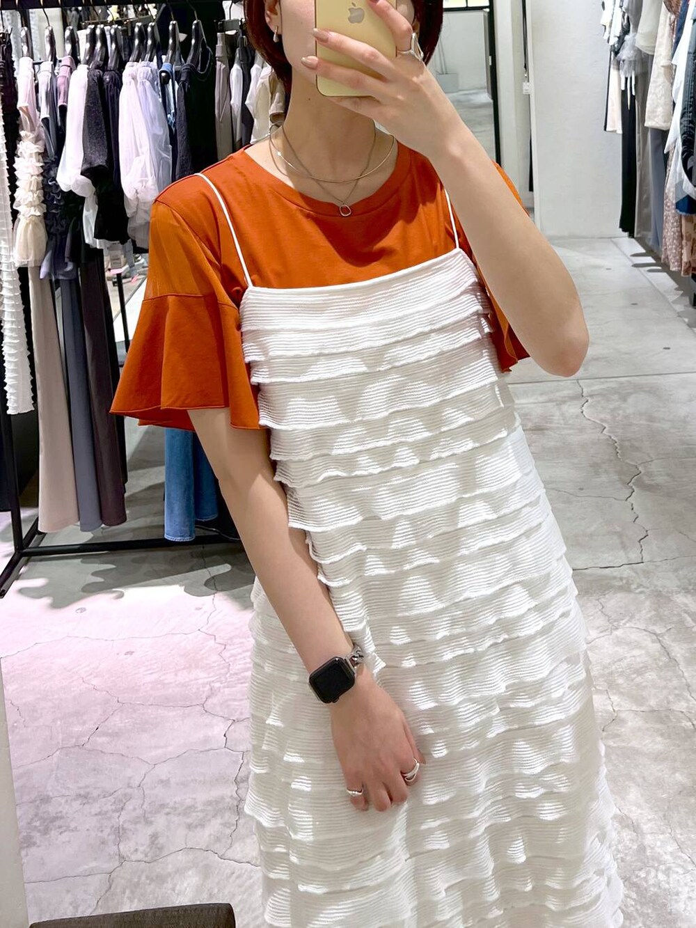 オレンジ系のTシャツ/カットソー、ホワイト系のワンピース、ブラック系のサンダルを着用したレディースの夏コーディネートの4枚目の写真