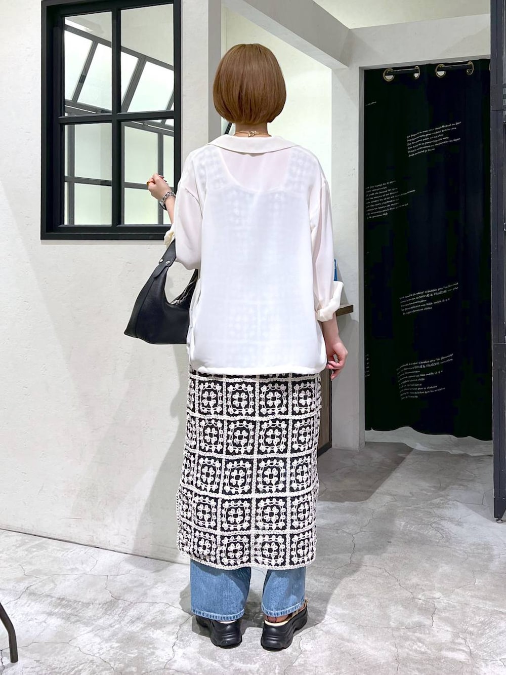 ブルー系のデニムパンツ、ベージュ系のサンダル、ブラック系のショルダーバッグを着用したレディースの夏コーディネートの3枚目の写真