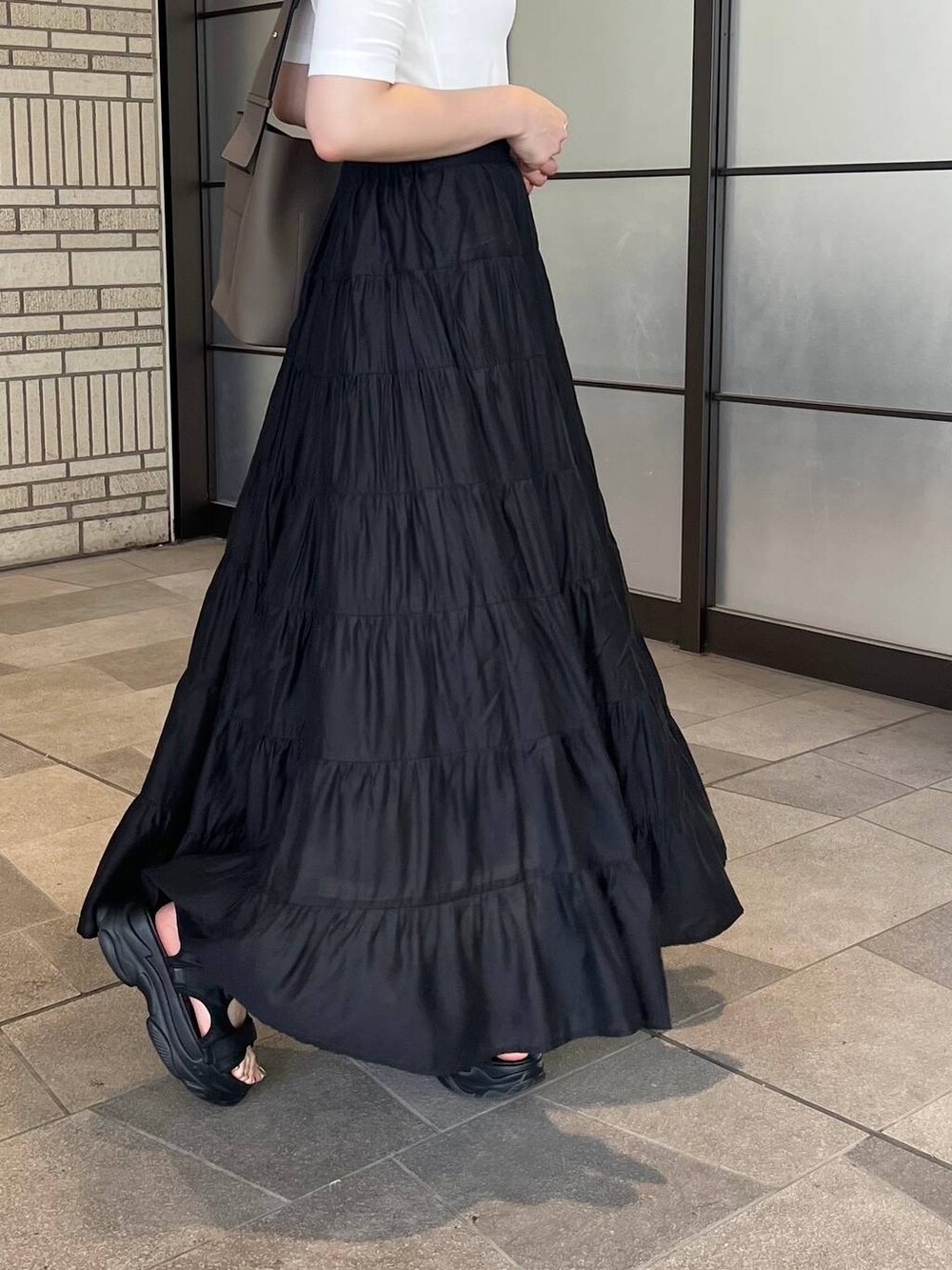 ベージュ系のサンダル、ブラック系のスカート、ホワイト系のTシャツ/カットソーを着用したレディースの夏コーディネートの4枚目の写真