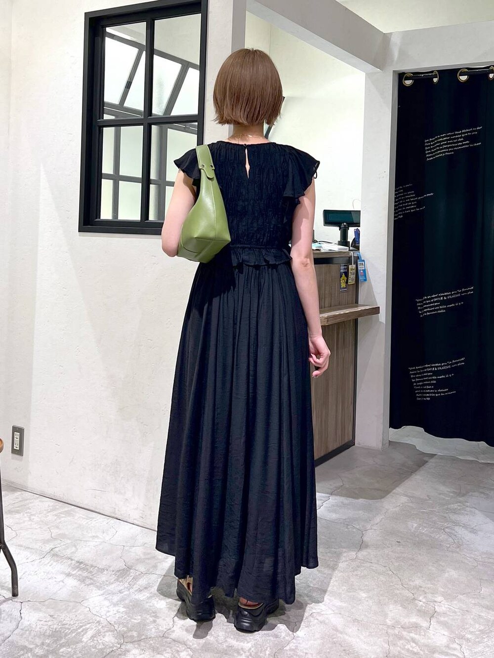 ベージュ系のサンダル、グリーン系のショルダーバッグ、ブラック系のワンピースを着用したレディースの夏コーディネートの3枚目の写真