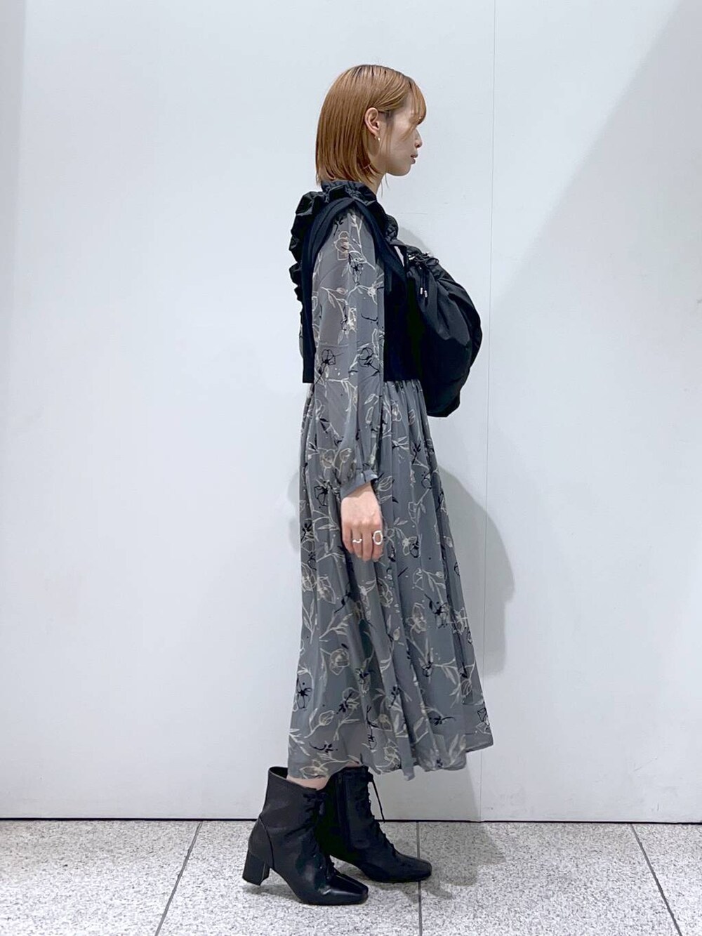 ブラック系のハンドバッグ、ブラック系のブーツ、グレー系のワンピースを着用したレディースの秋コーディネートの2枚目の写真