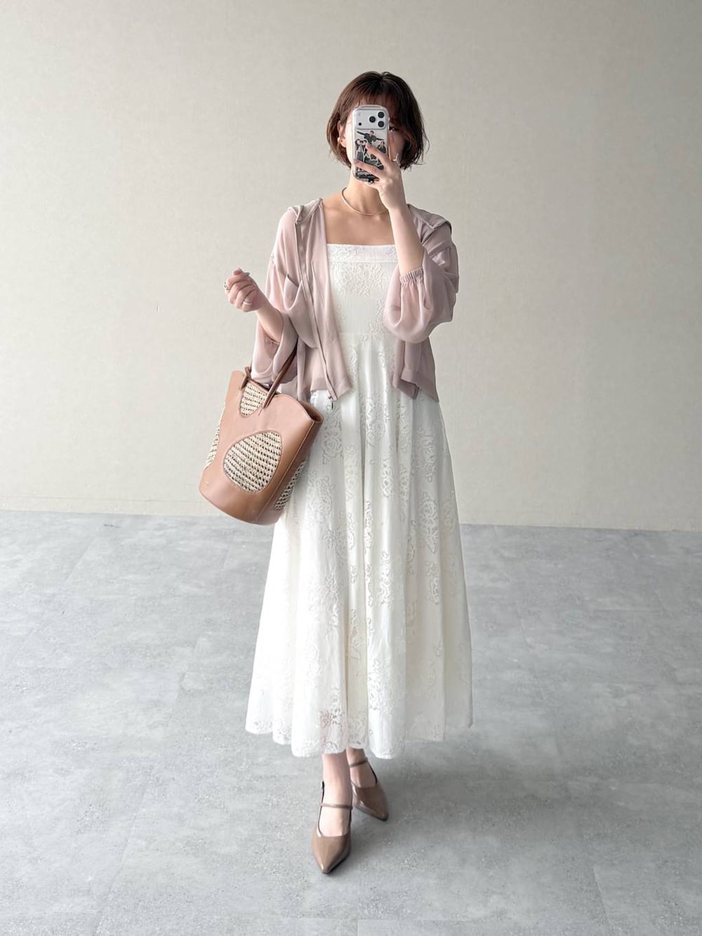 ベージュ系のパーカー、ブラウン系のトートバッグ、ホワイト系のワンピースを着用したレディースの春コーディネートの5枚目の写真