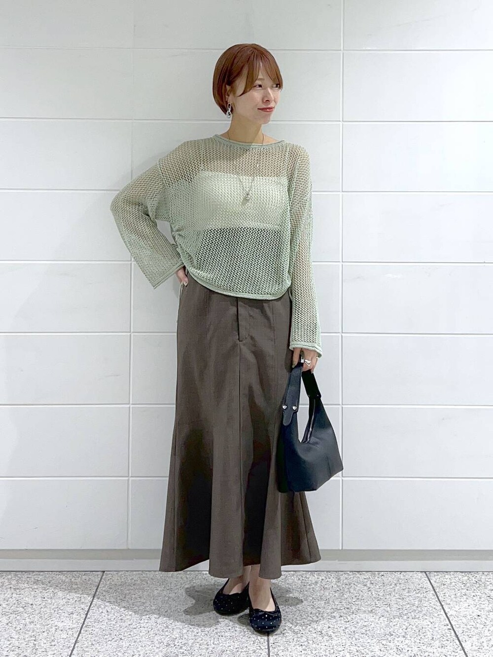 ブラック系のバレエシューズ、グリーン系のニット/セーター、グレー系のスカートを着用したレディースの春コーディネートの2枚目の写真