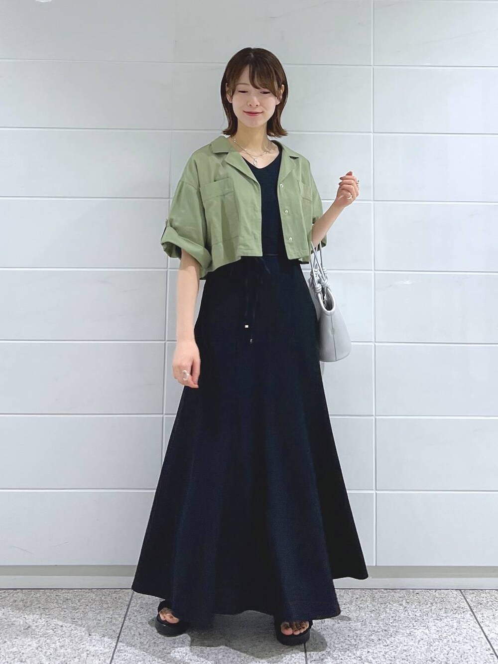 ブラック系のサンダル、シルバー系のハンドバッグ、グリーン系のミリタリージャケットを着用したレディースの夏コーディネートの2枚目の写真