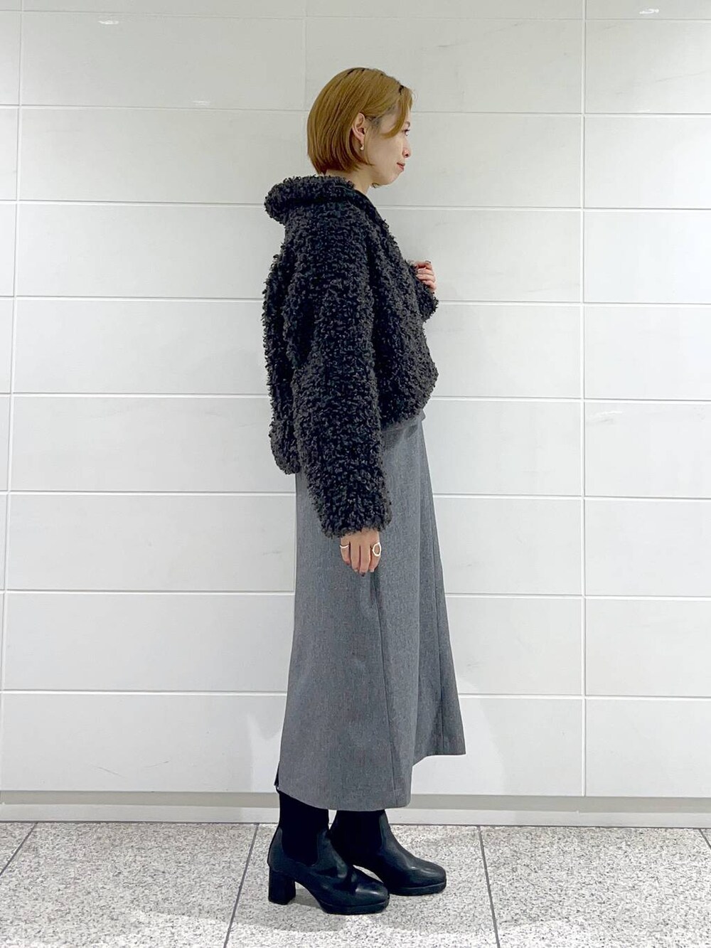 ブラック系のブルゾン、ブラック系のブーツ、グレー系のジャンパースカートを着用したレディースの秋コーディネートの2枚目の写真