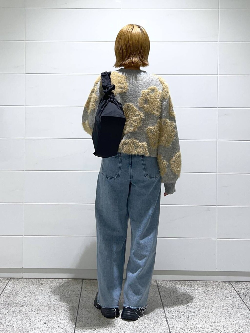 ブルー系のデニムパンツ、ブラック系のブーツ、ブラック系のショルダーバッグを着用したレディースの秋コーディネートの3枚目の写真