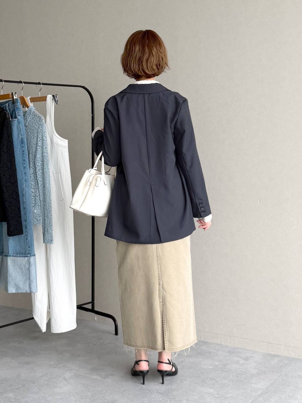 ブラック系のサンダル、ブルー系のテーラードジャケット、ベージュ系のスカートを着用したレディースの春コーディネートの3枚目の写真