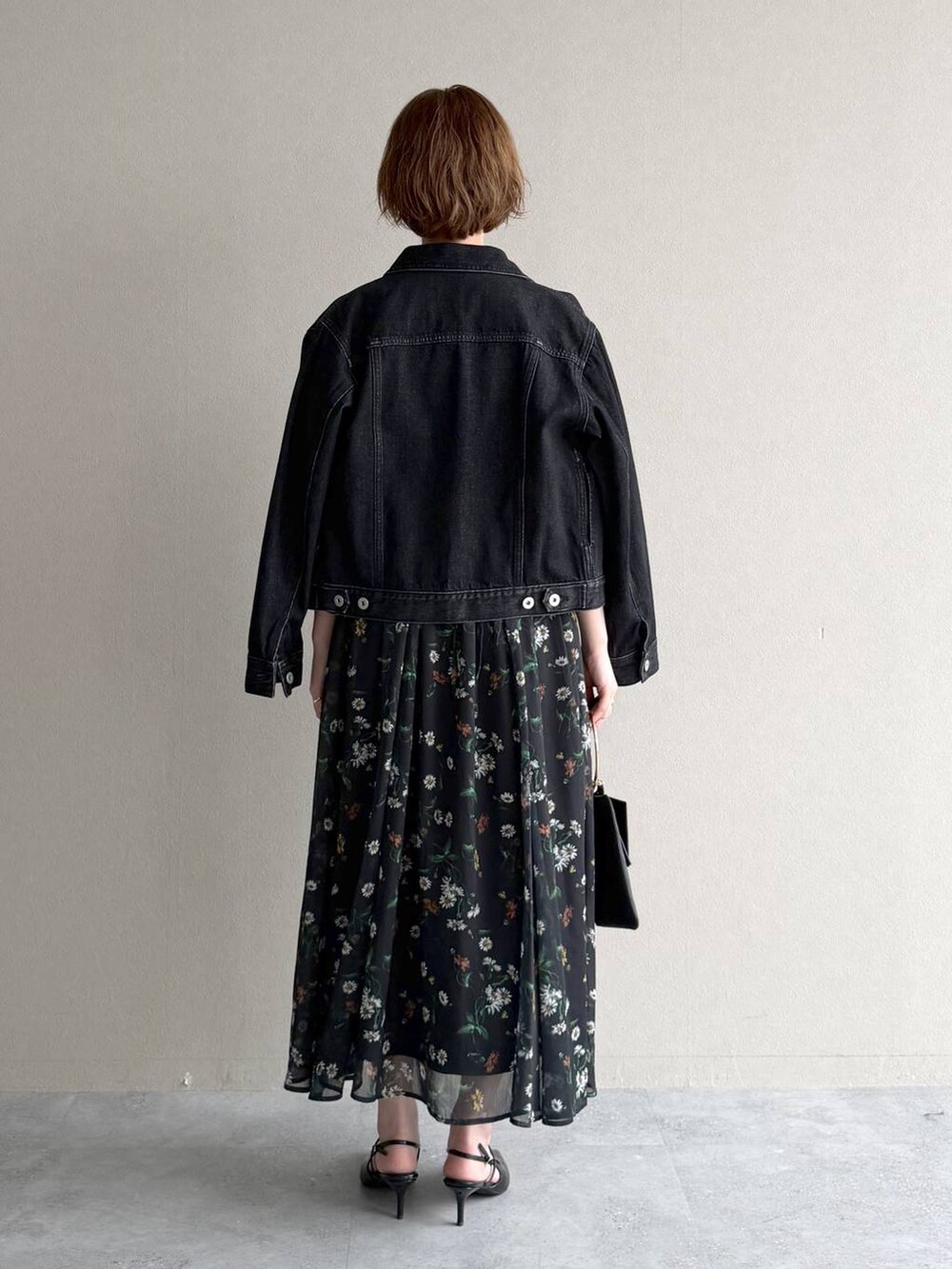 ブラック系のデニムジャケット、ブラック系のサンダル、ブラック系のショルダーバッグを着用したレディースの春コーディネートの3枚目の写真